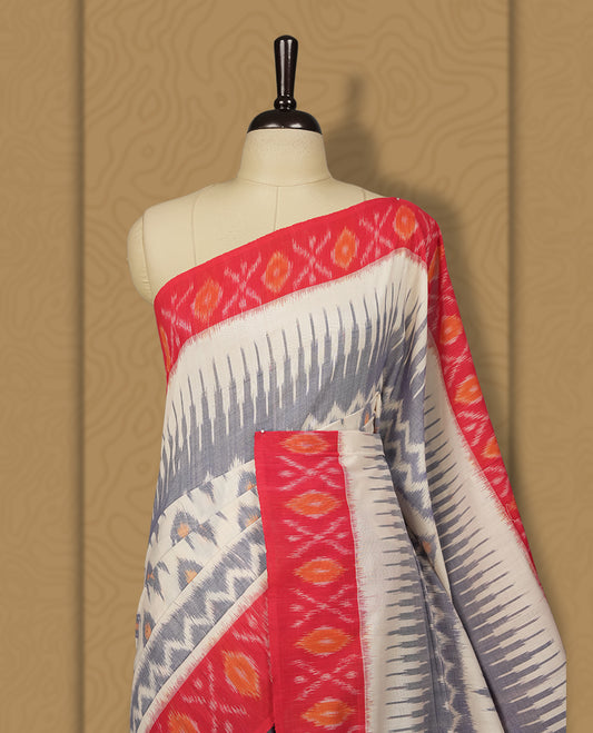 Off white colour Ikkat Pochampally saree adorned with blue & sandy brown geometric patterns, paired with a striking red border and pallu featuring traditional ikat motifs, a timeless blend of vibrance and tradition.