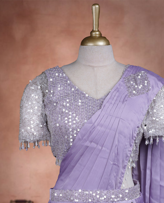 Elegant Lavender Colour ready to wear saree adorned with rich silver zari and bead embroidery along the border and pallu, paired with a heavily embellished matching blouse for a grand festive look.
