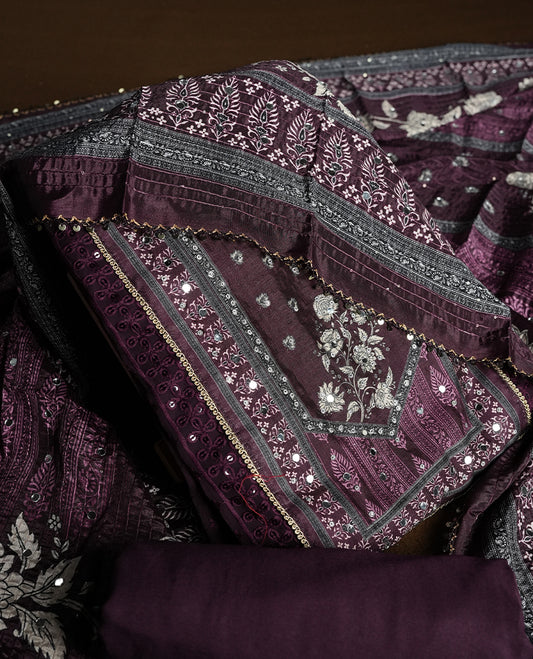 Dark purple colour churidhar material featuring Mirror and thread embroidery, foral print pattern on the self colour front panel, floral digital printed dupatta with elegant border, and matching plain bottom