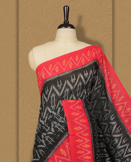 Black colour Ikkat Pochampally saree featuring bold geometric motifs in grey colour with a striking red colour contrast border with grey and orange colour zigzag & beautifully blending tradition with elegance.