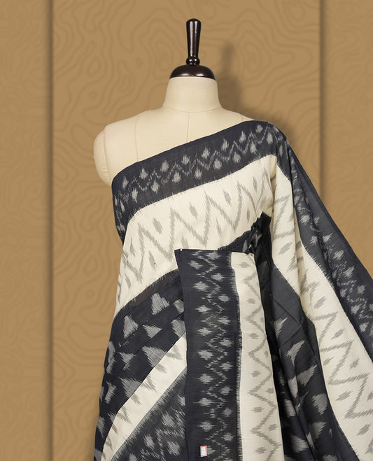 Black and Cream colour Ikkat Pochampally saree adorned with striking grey colour geometric motifs and a contrasting traditional border, The intricately woven pallu adds elegance, making it a timeless drape.
