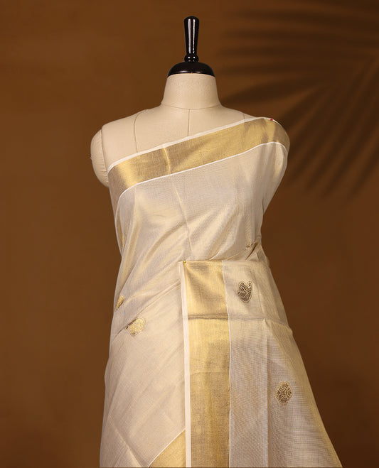 Classic Kerala Kasavu saree with golden motifs and a grand woven pallu, The ivory tone with intricate zari detailing makes it ideal for weddings and festivals, Pair with gold jewelry for a graceful, regal look.