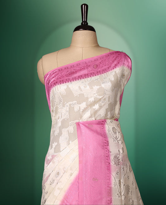 White colour saree adorned with delicate self woven motifs across the body, highlighted with a striking Pink woven border and pallu, finished with tassels, and paired with a matching blouse