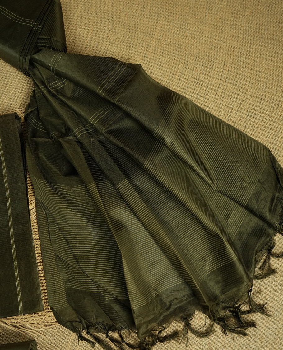 Army green colour tussar suit material featuring a subtle self woven pattern and vertical lines on the body, paired with a lightweight matching dupatta with tassel edges and a plain bottom piece.