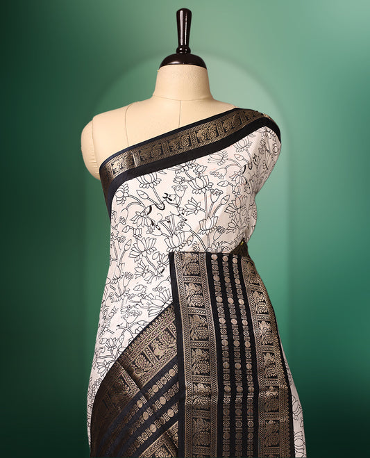 White colour saree adorned with striking black floral and cow prints across the body, enhanced by a rich black border for bold contrast, and paired with a matching blouse