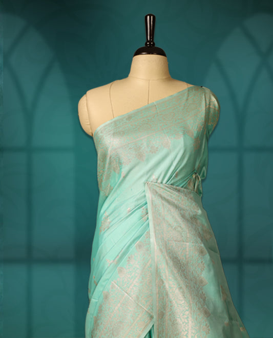 Sea green colour semi silk saree featuring delicate golden zari floral motifs across the body, complemented by a rich self colour woven border and pallu, paired with a matching blouse.