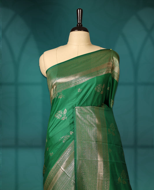 Green colour semi silk saree featuring golden zari floral motifs all over the body, complemented by a rich self colour woven border, with matching blouse.