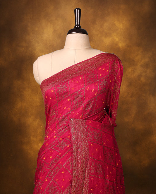 Reddish pink Banarasi Bandhani saree featuring Bandhani dots in checkered zari motifs, a beautifully woven zari border, and a grand pallu with tassels. A graceful pick for festive and wedding wear.