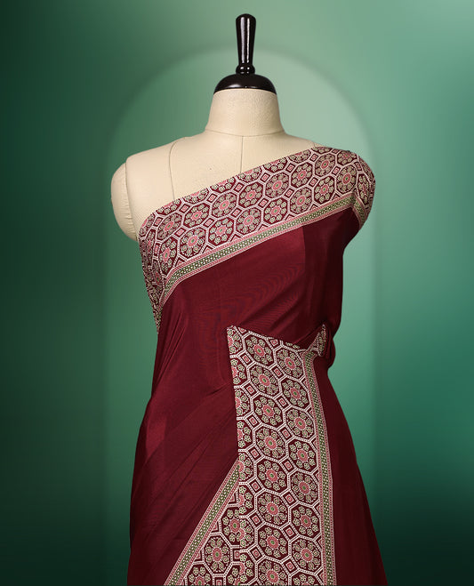 Deep Red colour semi modal saree featuring an ethnic patterned border and pallu in contrasting beige and maroon hues, highlighted with traditional floral motifs, and paired with a matching blouse