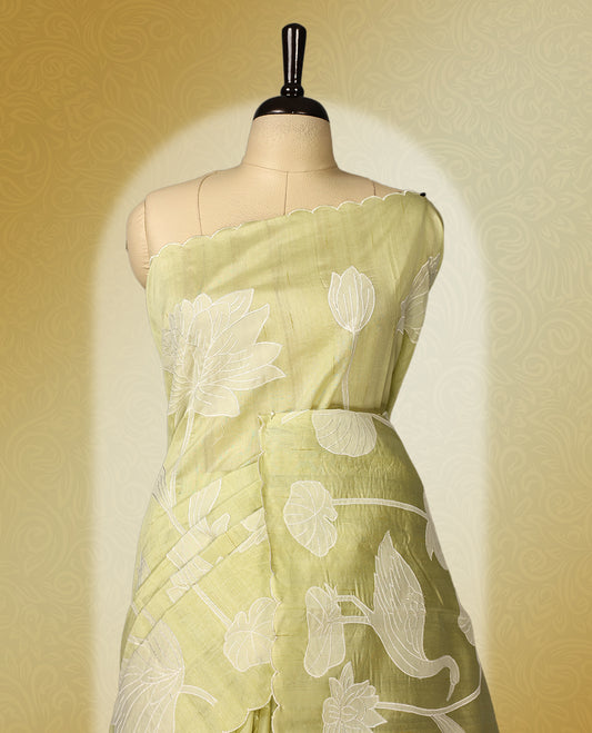 Pastel yellow colour semi tussar saree adorned with elegant white applique work in leaf and floral designs across the body and border, paired with a matching blouse.