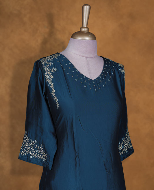 Teal blue colour kurti by Talisha with V neckline, scattered stud detailing on the yoke, A‑line calf‑length silhouette, and three‑quarter sleeves featuring delicate floral embroidery.