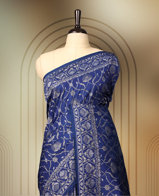 Blue Banaras soft silk saree with silver zari floral vines on the body, intricately woven border, and a grand pallu with bold paisley motifs, Comes with a matching blouse & perfect for elegant occasions.