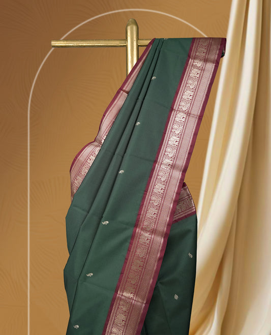 Dark green colour soft silk saree with silver buttas, enhanced by a vibrant maroon zari border and pallu, paired with a matching blouse.