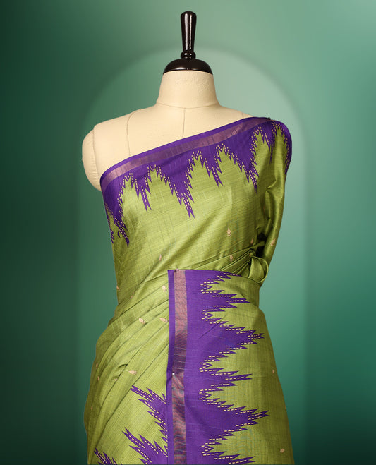 Green colour saree adorned with subtle woven motifs on the body, enhanced with a striking Purple Temple patterned border, complemented by a rich Purple striped pallu with tassels, and paired with a matching blouse