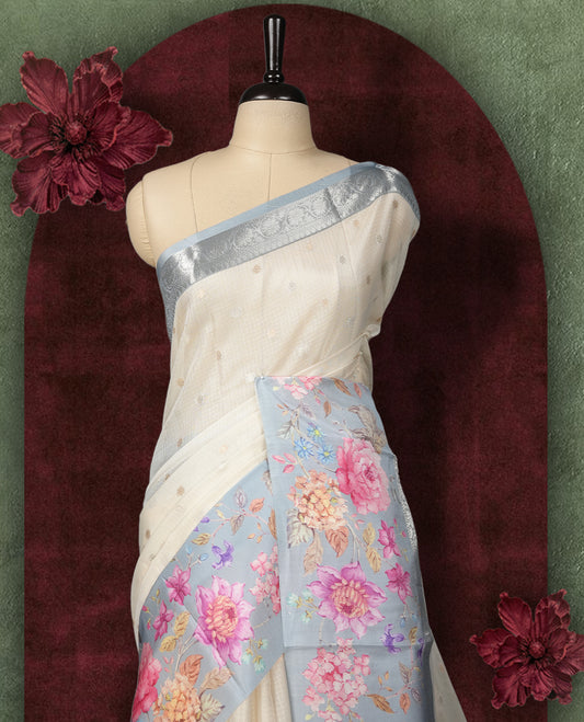 Ivory colour Kotta Tussar Silk saree features a vibrant digital floral print with small gold zari motifs on the body, and elegant grey colour banarasi border & Paired with a matching blouse,blending modern design with traditional elegance.