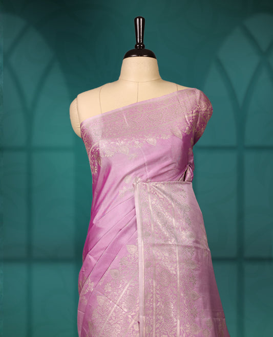 Lavender colour semi silk saree featuring delicate golden zari floral motifs across the body, complemented by a rich self-colour woven border and pallu, paired with a matching blouse.