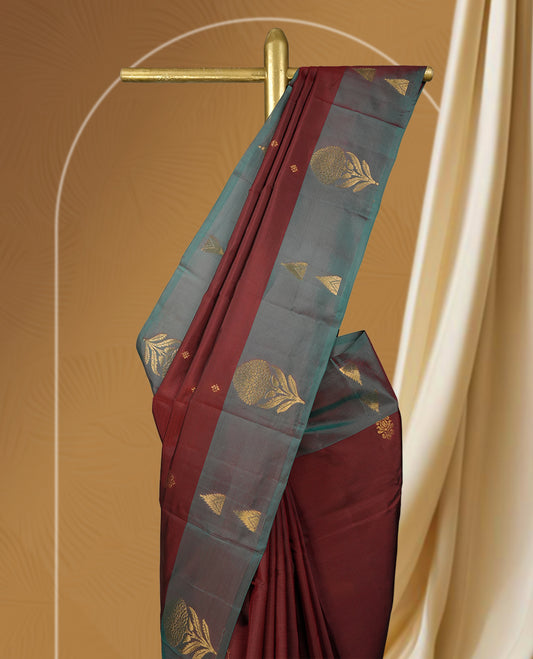 Dark maroon colour soft silk saree with a stunning maroon and teal green colour double shaded border, rich golden zari motifs, and a paired matching blouse.