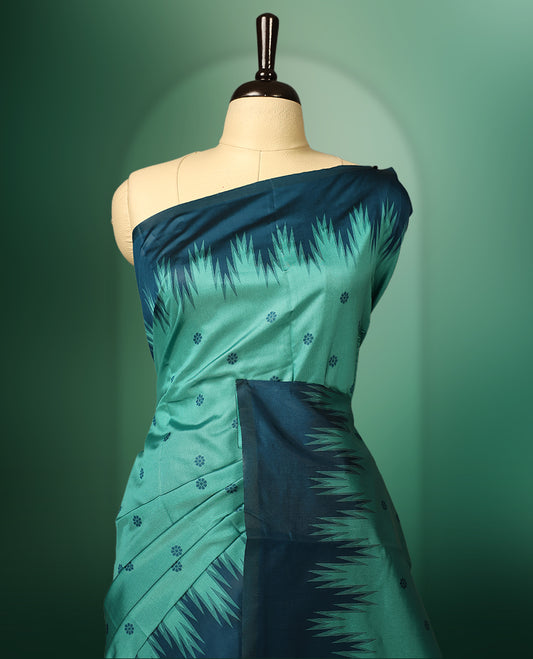 Sea green colour saree highlighted with subtle dotted motifs, complemented by a deep teal border featuring bold Ikat inspired patterns and striped pallu, paired with a matching blouse