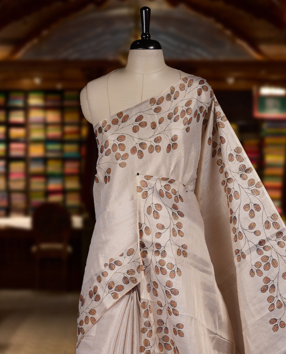 Beige colour Semi tissue saree adorned with earthy toned digital leaf prints on the body and an elegant pallu & comes with a matching blouse piece