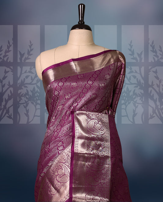 Grape colour semi silk brocade saree featuring intricate golden zari floral and geometric patterns all over the body, complemented by a rich self-colour woven border and pallu, paired with a matching blouse.