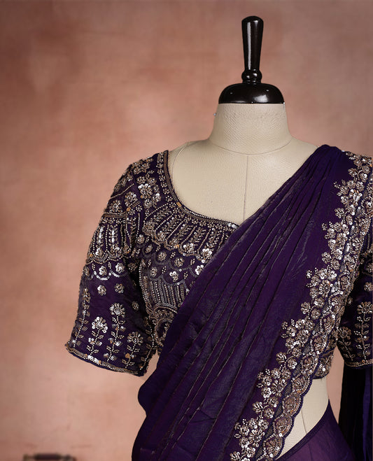 Elegant deep purple ready to wear saree adorned with rich silver zari and bead embroidery along the border and pallu, paired with a heavily embellished matching blouse for a grand festive look.