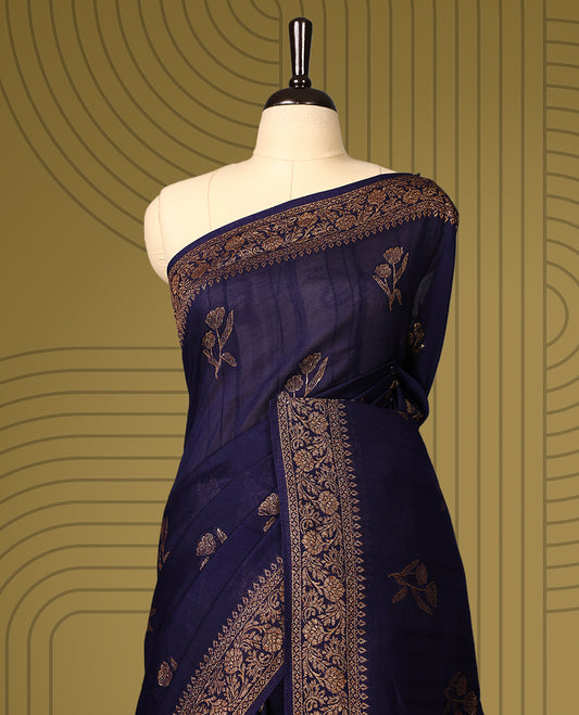 Navy blue semi Banaras tussar saree adorned with golden floral motifs in diagonal patterns across the body and a finely woven zari border, finished with a rich golden pallu, paired with a matching blouse.
