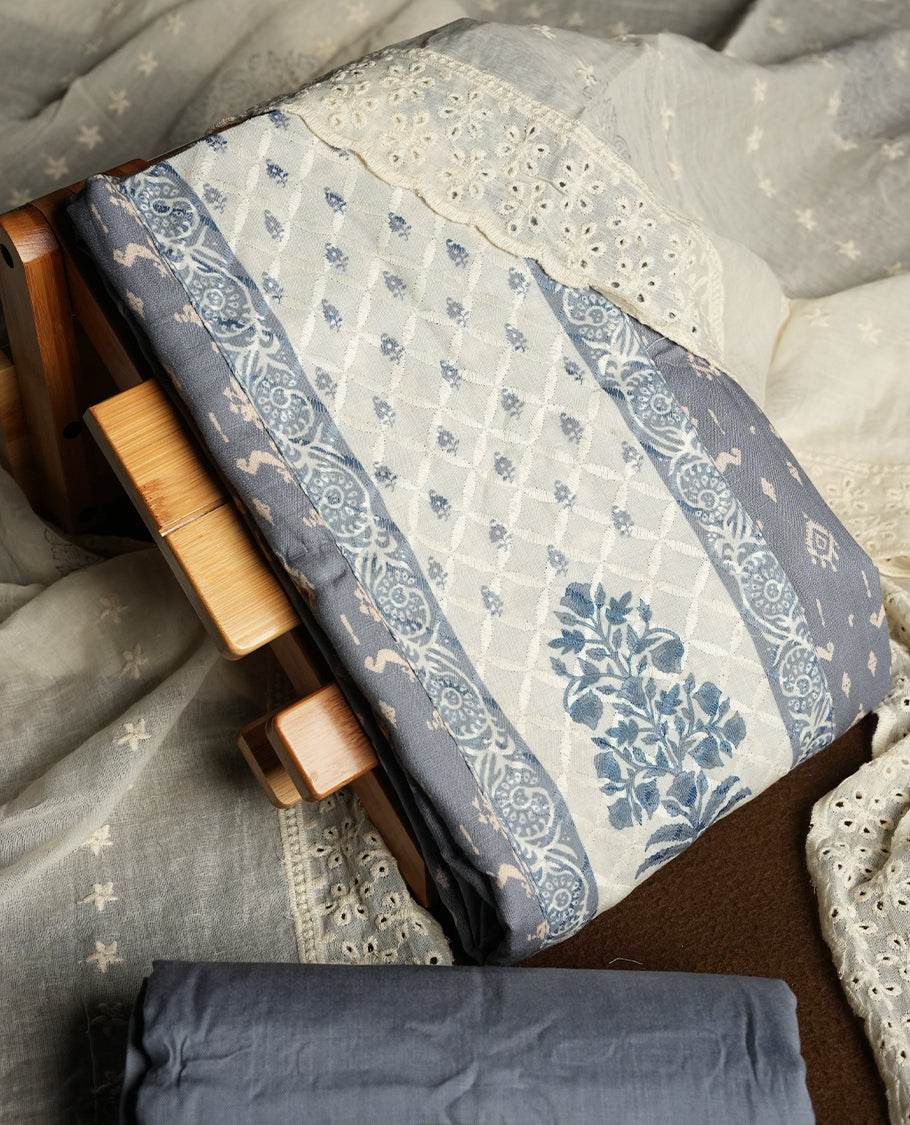 Grey and off white colour churidar material featuring elegant thread work on the neckline and floral motifs on the body, dupatta is adorned with delicate embroidered motifs and scalloped lace border & Comes with a matching bottom.