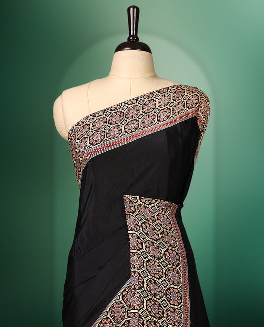 Black colour semi modal saree featuring an intricately woven multicolour ethnic patterned border and pallu, highlighted with traditional motifs, and paired with a matching blouse