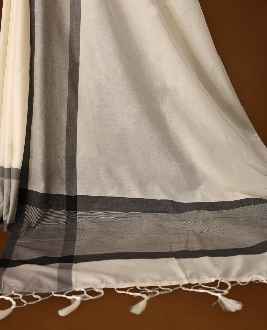 Elegant off white colour Kerala cotton saree with soft grey and charcoal borders, finished with tassel detailing,Lightweight and breathable, it comes with a matching blouse & perfect for everyday, festive, or office wear.
