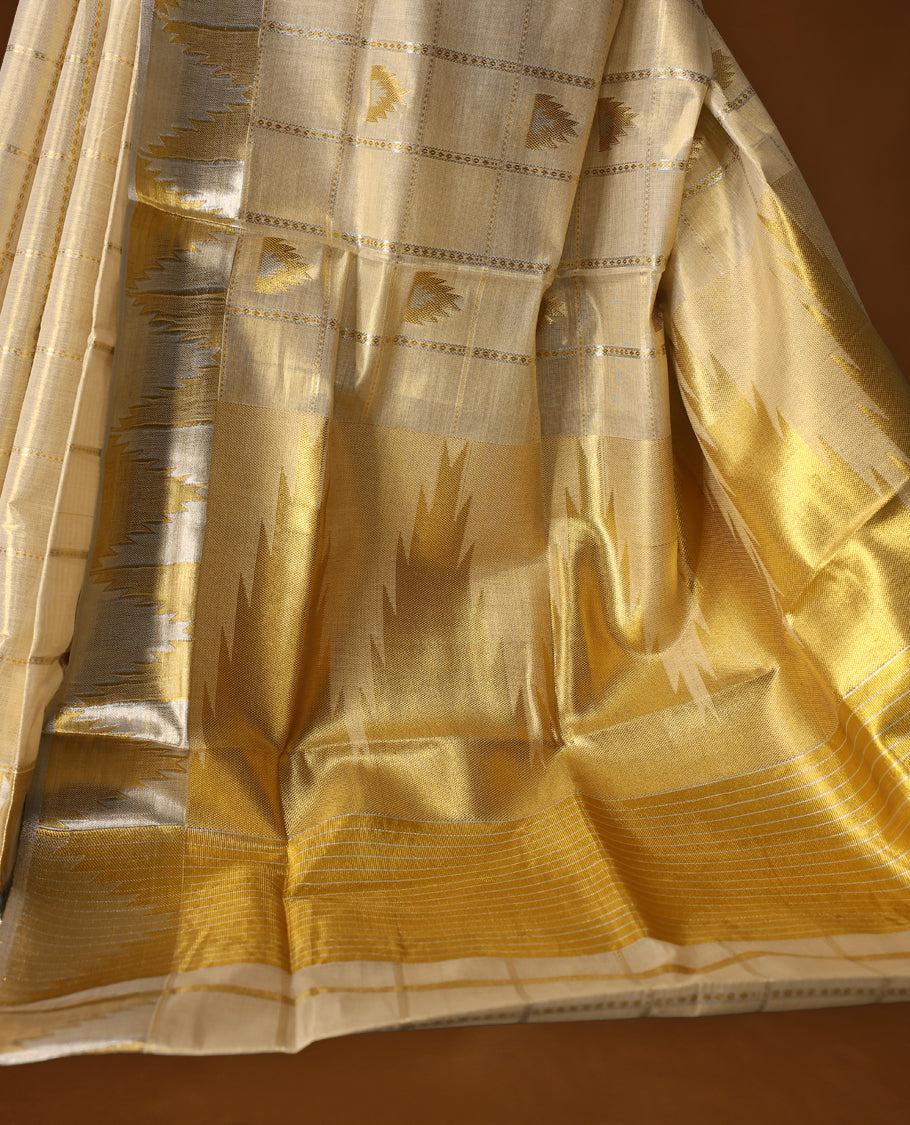 Elegant off white colour Tissue Kerala saree adorned with silver and gold geometric motifs on a checked body, enhanced by a shimmering silver kasavu border and rich golden pallu, paired with matching blouse for festive elegance.