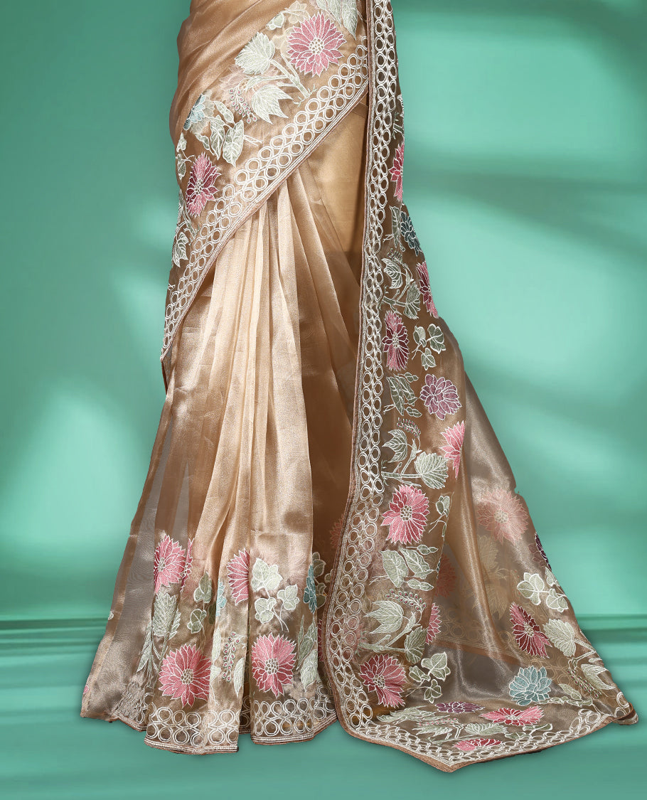 Light Brown colour organza designer saree featuring delicate pastel floral embroidery in pink, mint green, and white across the body, with a scalloped border accentuated by floral threadwork, and a gracefully embroidered pallu paired with matching blouse.