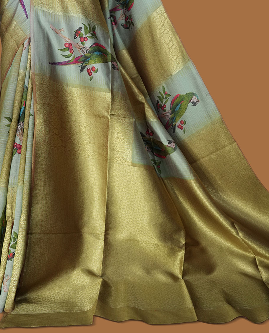 Parrot Green colour semi tussar Banarasi saree featuring vibrant multi-color floral prints across the body, with geometric zari patterns, and a matching blouse detailed with silver woven buttas.