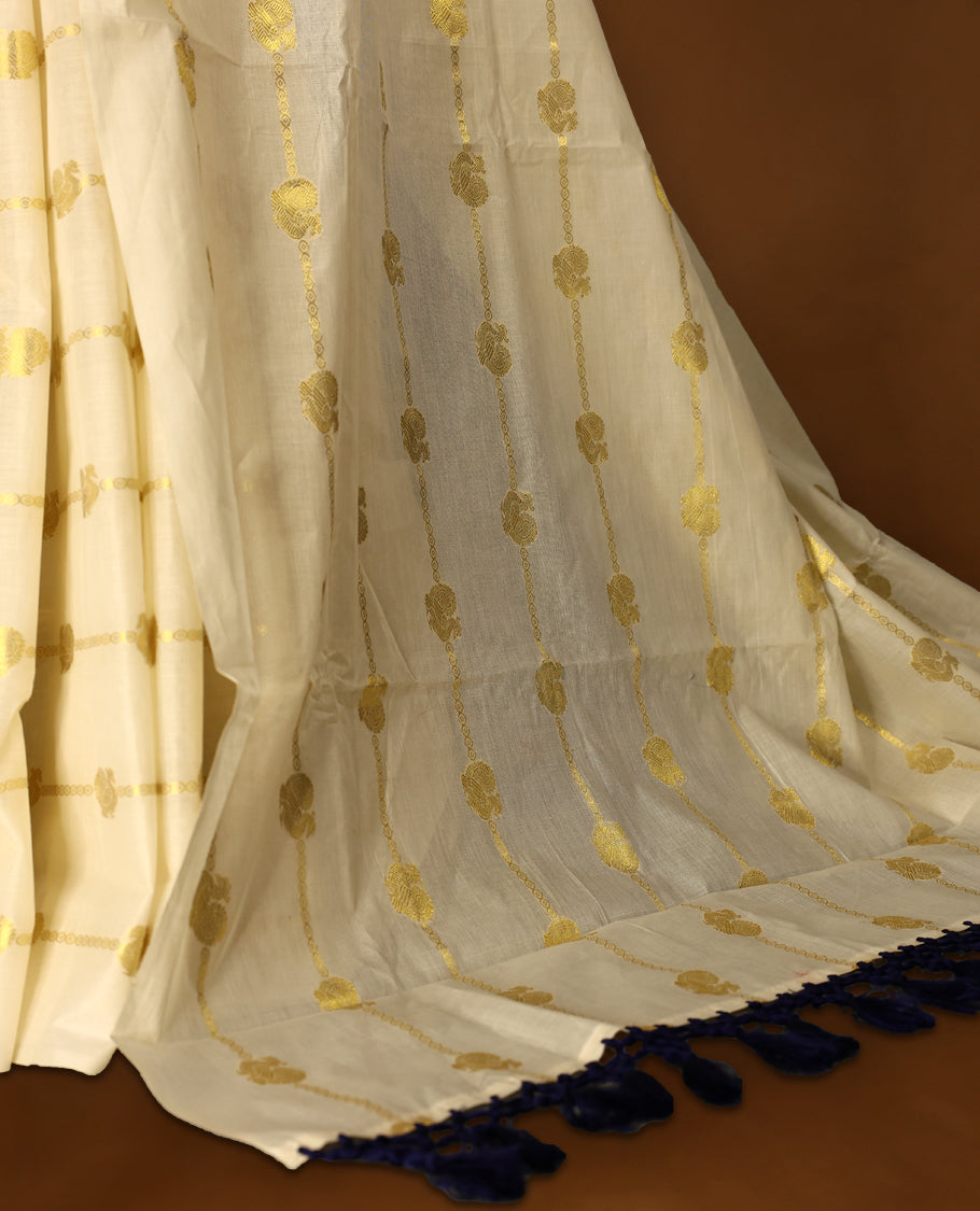 Elegant off white colour cotton Kerala saree featuring a gold Zari stripes with peacock motifs on body, with Blue colour tassels offering a classic and graceful look, paired with a matching blouse.