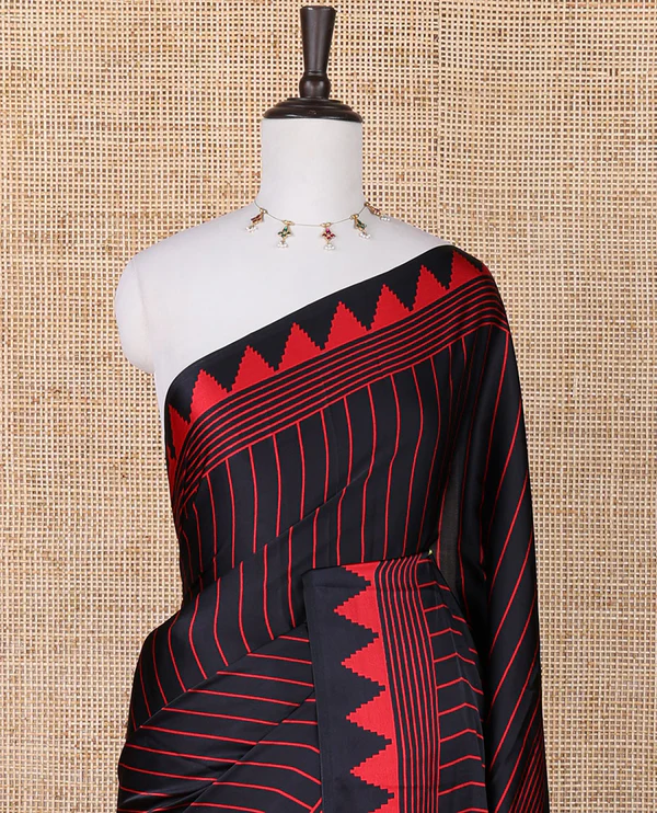 Black sem imodal crepe saree adorned with red vertical line prints, complemented by a temple border and circle butta design on the pallu, paired with a matching printed blouse.