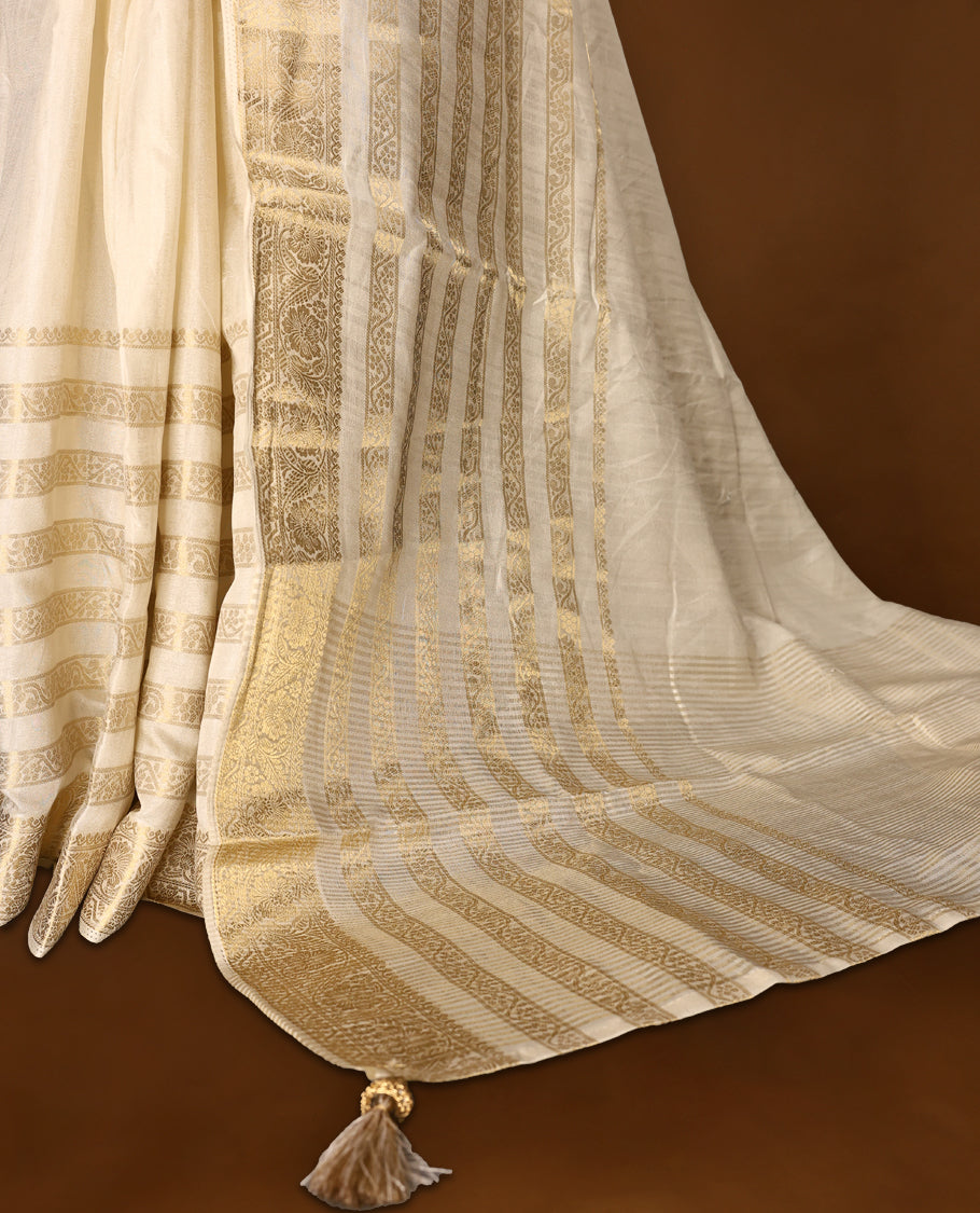 Ivory white Colour Tussar Kerala saree with a sheer, smooth body and soft golden sheen, Accented with fine zari stripes and an intricate floral zari border,Comes paired with a coordinated matching blouse piece.