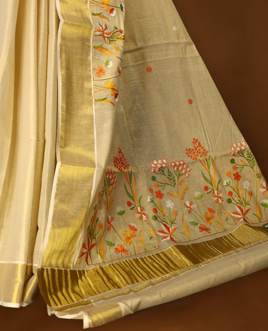 Light Gold colour Tissue Kerala saree featuring Orange and white Colour Floral thread work on body and a beautifully woven Gold Kasavu border, paired with a matching blouse perfect for festive occasions.