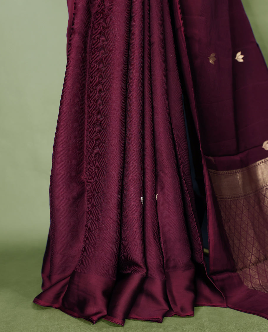 Maroon colour crepe Banaras saree featuring small zari Floral Motifs across the body, without border, a sleek texture, and a rich golden zari pallu with geometric patterns, paired with a matching blouse for a graceful festive look
