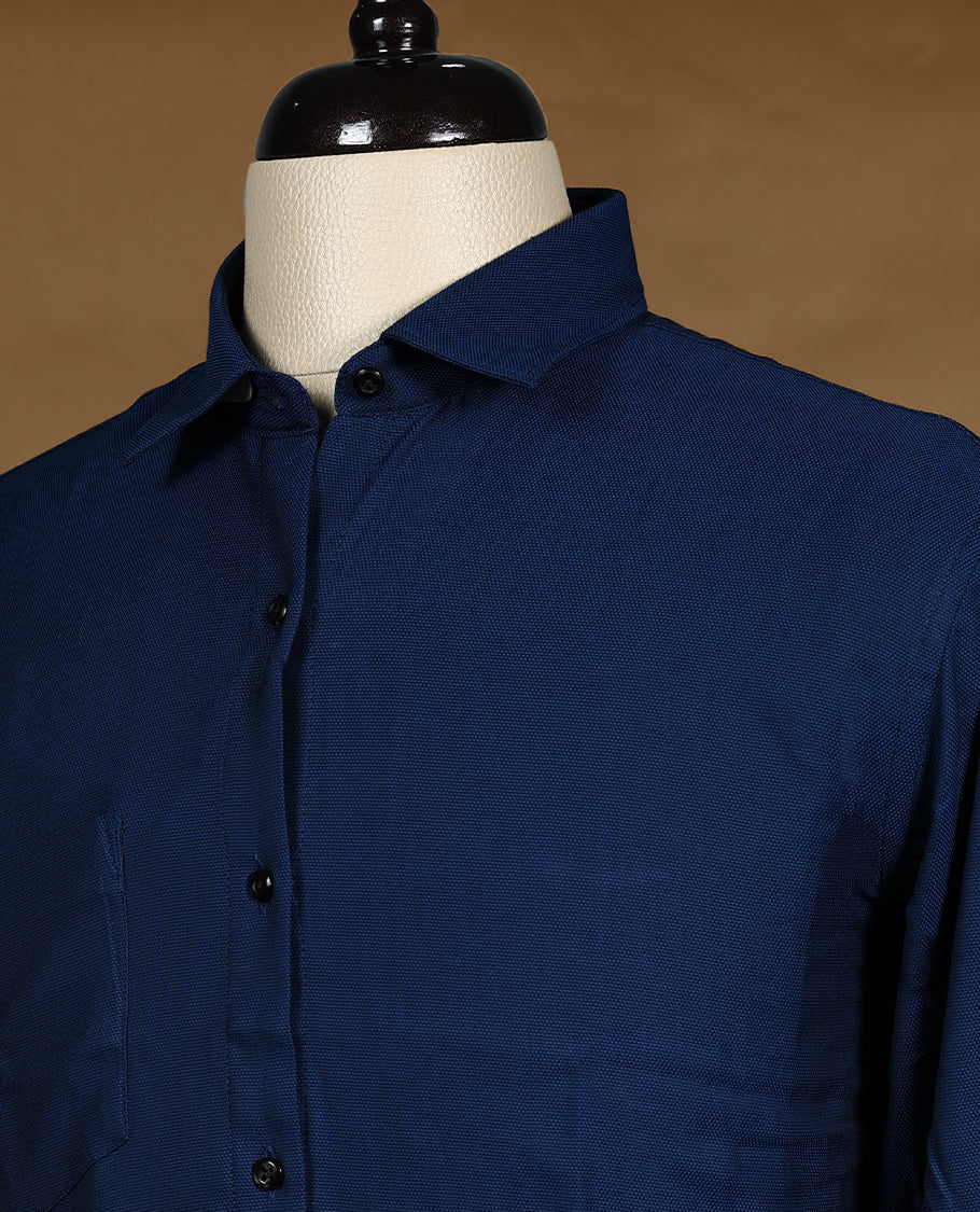 Deep blue colour Peter Eglend men’s shirt in a relaxed formal fit, featuring a smooth plain finish with full sleeves, classic collar, and chest pocket ideal for office and semi formal occasions.