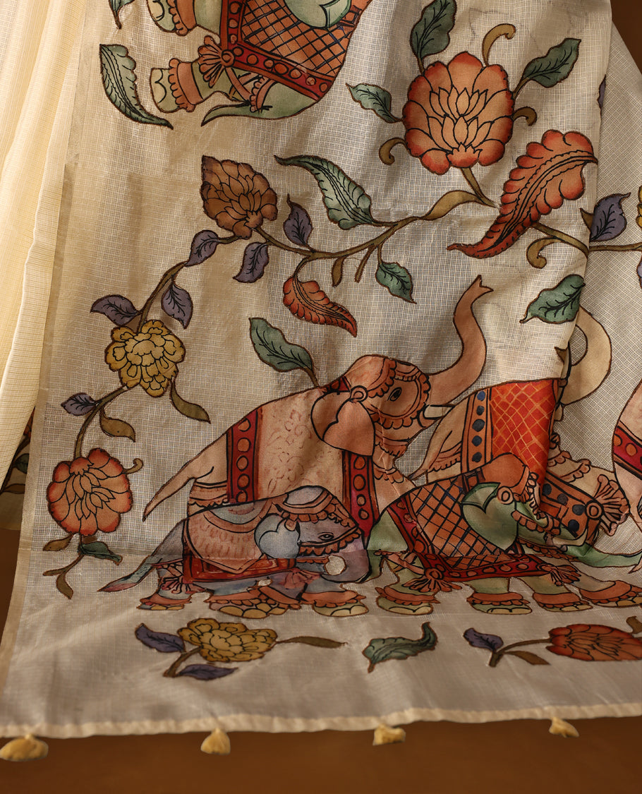 Elegant off white colour Kota net saree featuring intricate hand painted Kalamkari motifs on the pallu and floral accents on the pleats, blending tradition with artistry & Perfect for festive occasions and graceful styling.