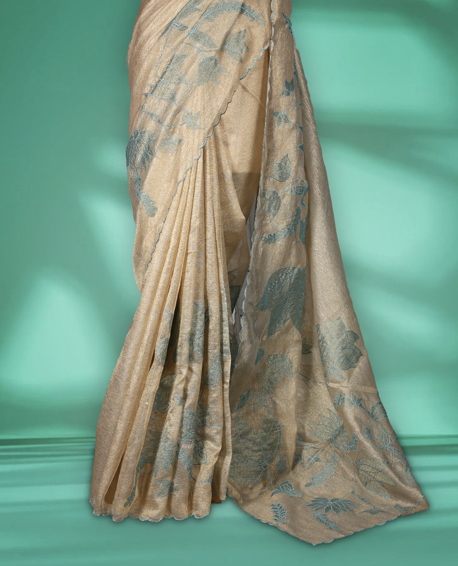 Champagne beige colour organza designer saree featuring subtle woven texture on the body, adorned with soft Blue floral embroidery along the border and pallu, finished with scalloped Thread edging paired with matching blouse.