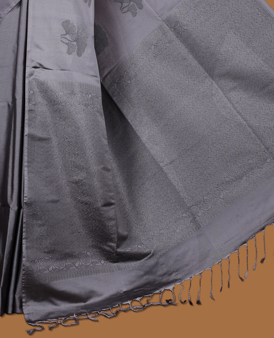 Silver gray colour semi soft silk saree adorned with delicate woven floral kodi motifs on the body, complemented by a Self colour woven pallu with intricate detailing and tassel accents without border & Comes with a matching blouse piece.