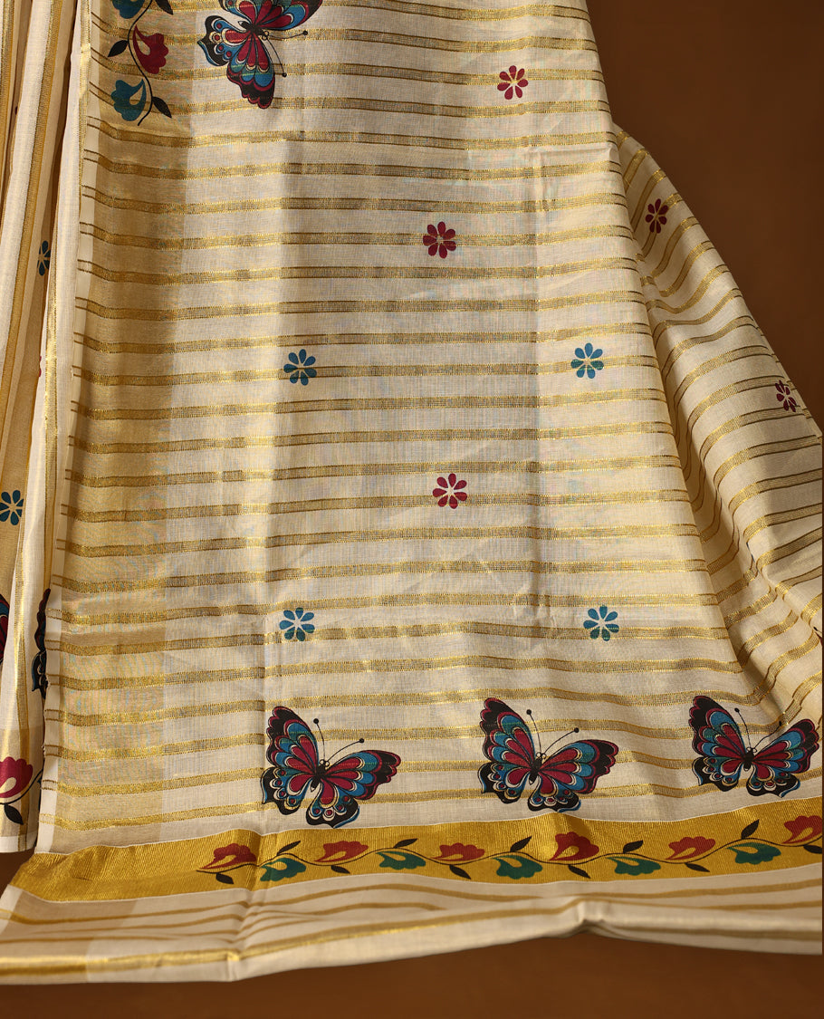 Elegant off white Kerala tissue saree with golden stripes, adorned with multicolor butterfly and floral motifs, and finished with a rich golden zari border with kodi prints perfect for a festive, graceful look with matching blouse.
