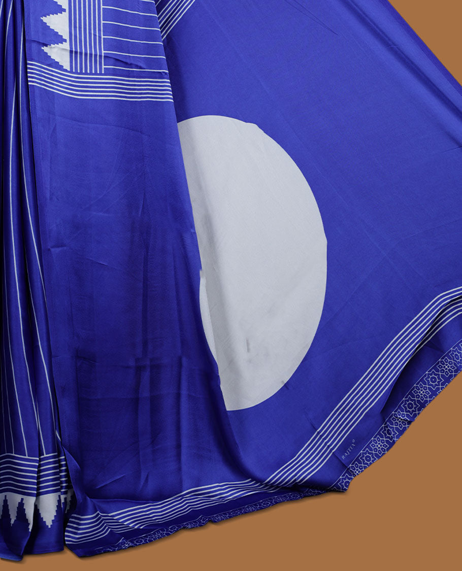 Royal blue colour semi modal saree featuring white colour geometric borders and fine stripe detailing, finished with an oversized circular motif on the pallu, paired with a matching printed blouse.