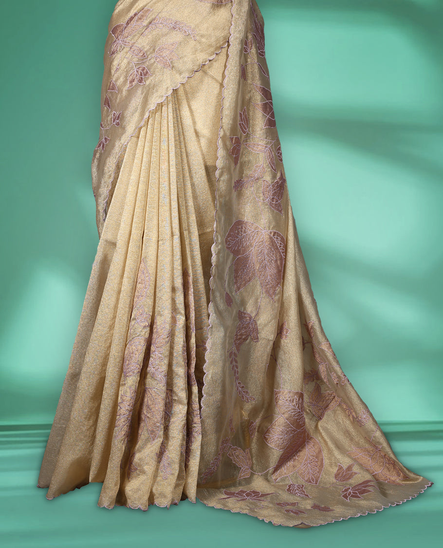 Champagne beige colour organza designer saree featuring subtle woven texture on the body, adorned with soft mauve floral embroidery along the border and pallu, finished with scalloped Thread edging paired with matching blouse.