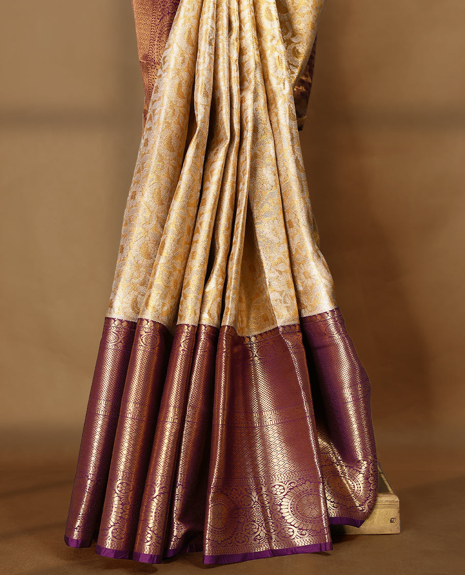 Gold colour tissue brocade saree with gold and silver zari floral pattern on body, gold zari traditional floral and chakkram work royal purple border, rich matching pallu with Antique zari motifs, paired with matching blouse.