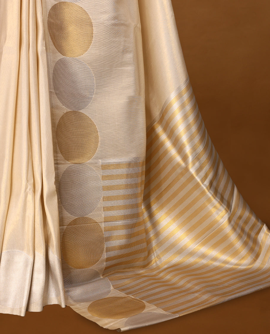 Muted gold Colour soft tissue Kerala saree featuring Plain body, Gold nad silver zari circle motifs on border, paired with a matching blouse.