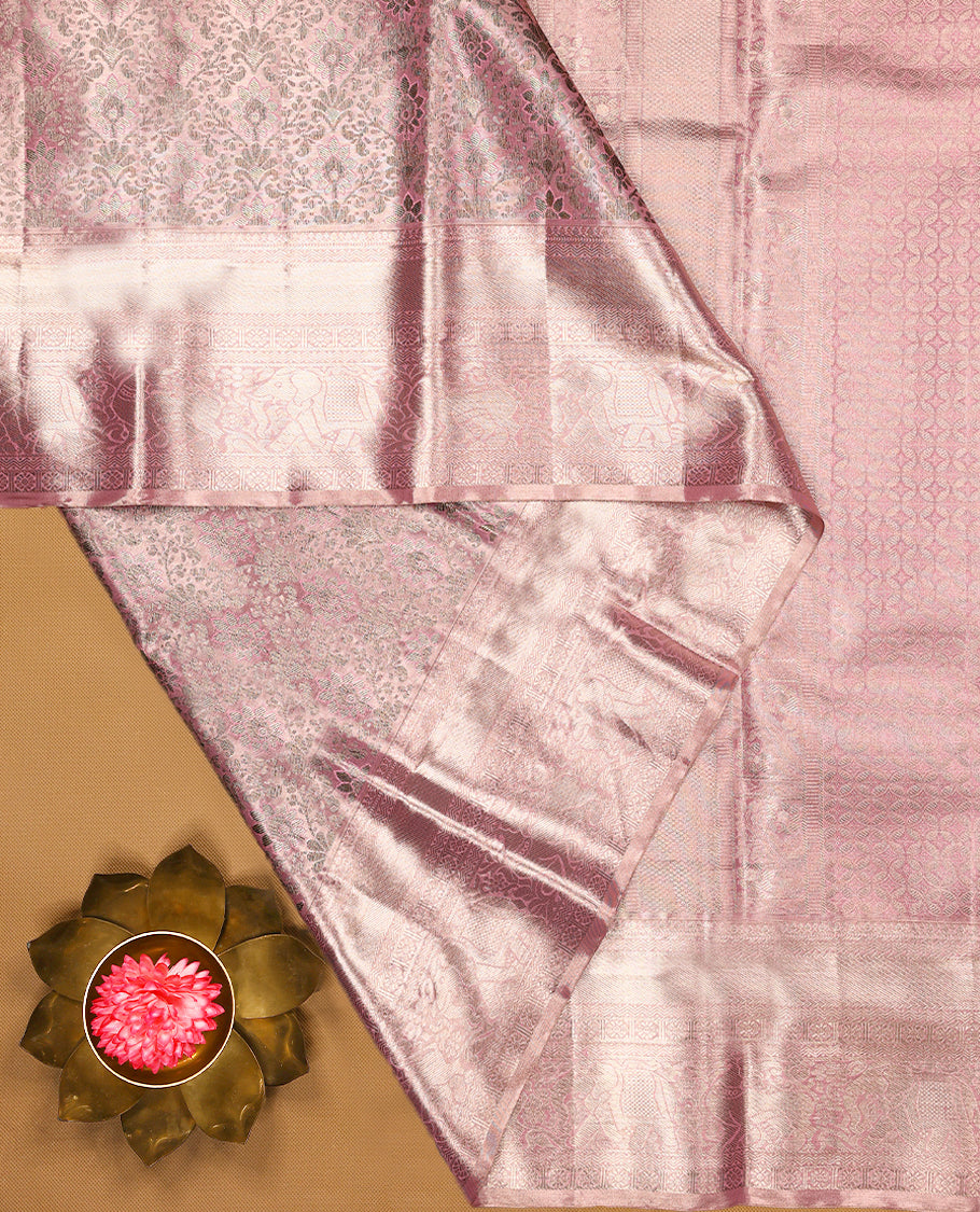 Pastel pink Colour Kancheepuram tissue silk saree adorned with intricate antique zari floral motifs on the body, beautifully complemented by traditional elephant and Chakkram design border, and paired with a matching blouse.