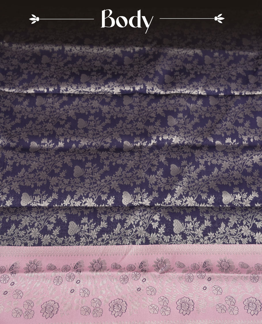 Navy blue colour semi silk saree adorned with subtle silver floral patterns on the body, complemented by contrasted a pastel light pink pallu intricately  woven with rich floral patterns border and pallu, and paired with a matching blouse