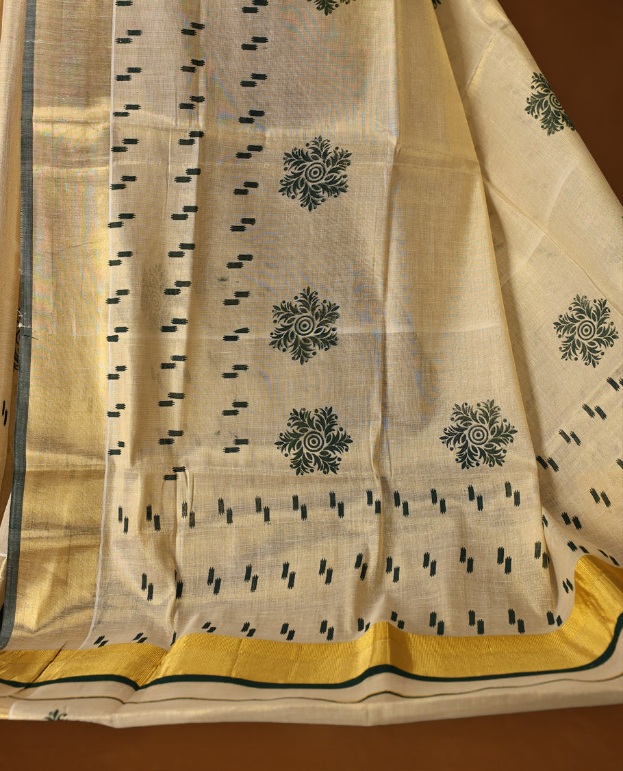Elegant off white tissue Kerala saree with green woven motifs and floral buttas, paired with a rich golden zari border and pallu paired with matching blouse.