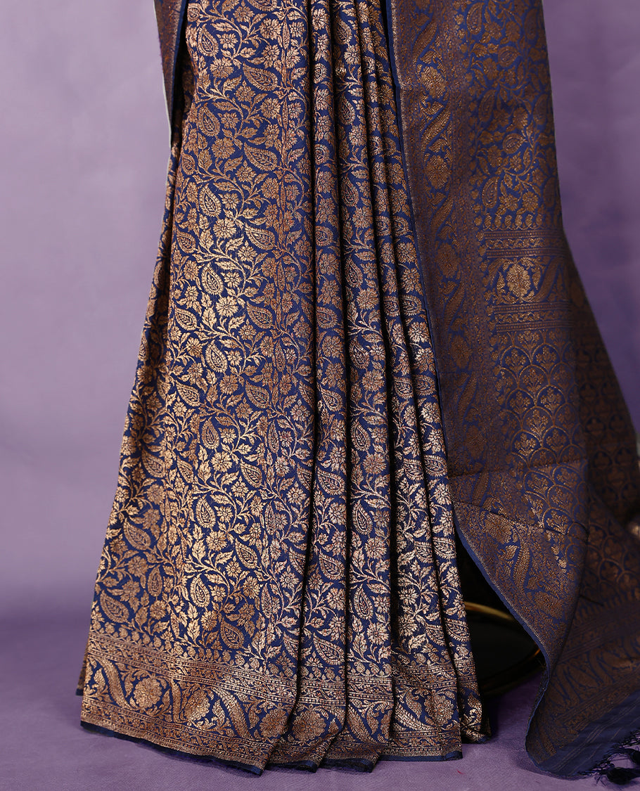 Navy blue colour semi Banaras Katan silk saree featuring intricate Antique Bronze zari floral and vine patterns woven throughout the body, enhanced with a rich traditional border and detailed pallu, paired with a matching blouse piece.